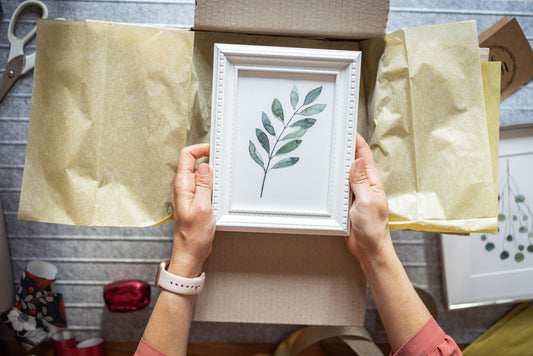 person carefully unwrapping framed piece of art